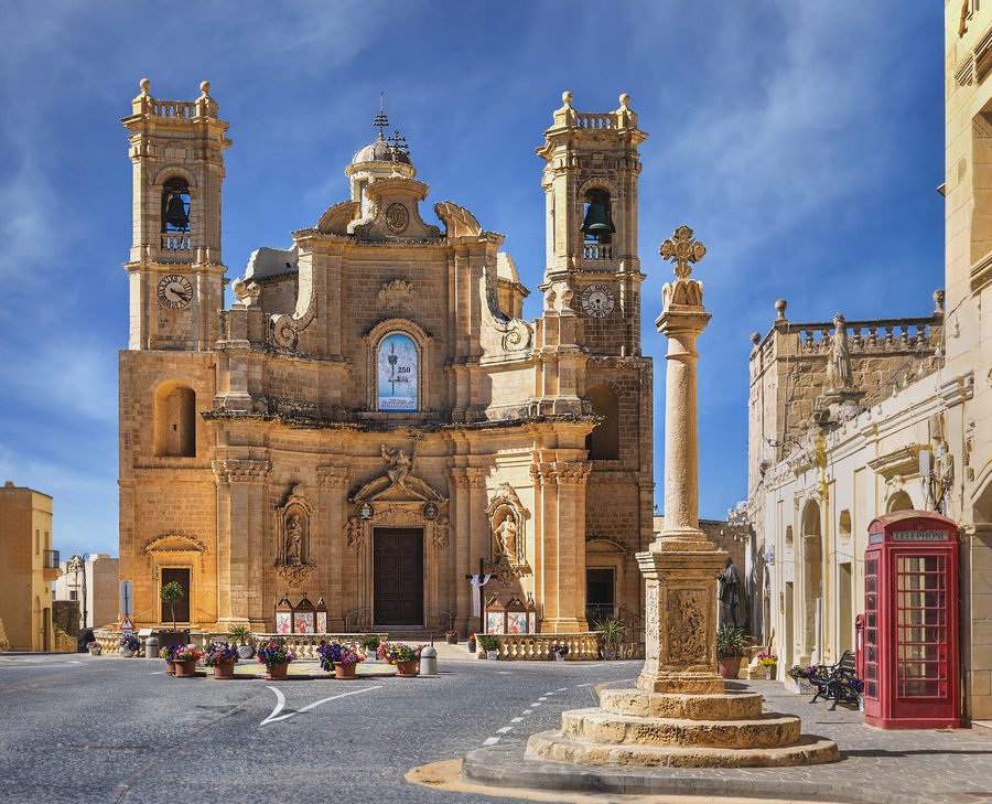 The baroque facade of the Basilica of the Visitation and the Dejma Cross in Gharb's main square